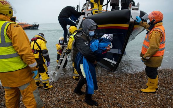 Des migrants sont assis sur la plage après avoir été aidés par un bateau de sauvetage de la RNLI (Royal National Lifeboat Institution) sur une plage de Dungeness, dans le sud-est de l'Angleterre.