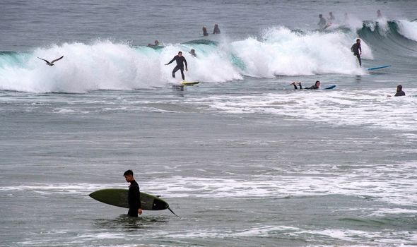Les surfeurs prennent l'eau juste au nord de la jetée de Newport à Newport Beach tôt le samedi matin 15 janvier 2022, après qu'un avis de tsunami a été émis pour Hawaï et les États-Unis.