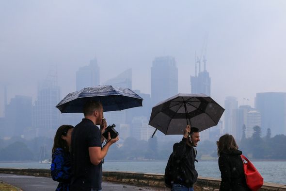 Des personnes debout pendant que la pluie tombe à Sydney