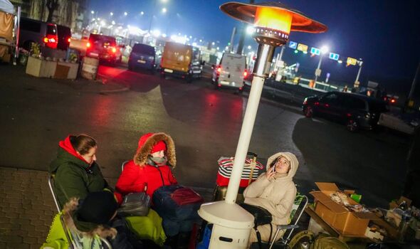Des femmes réfugiées se réchauffent sous un champignon chauffant tôt le matin à la frontière ukraino-polonaise à Medyka.