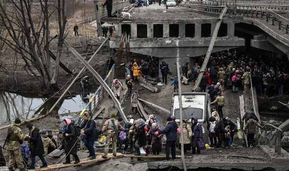 Les gens traversent un pont détruit alors qu'ils évacuent la ville d'Irpin, au nord-ouest de Kiev