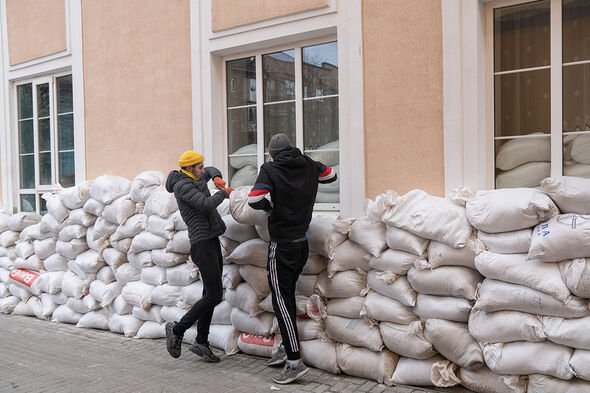 Personnes plaçant des sacs de sable à côté d'un centre culturel local à Ivano-Frankivsk, Ukraine