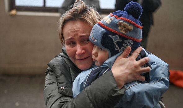 Une femme tient son enfant alors qu'elle essaie de monter à bord d'un train gratuit vers la Pologne dans une gare de Lviv