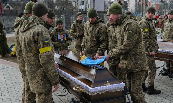 Des militaires ukrainiens couvrent le cercueil d'un soldat ukrainien tué