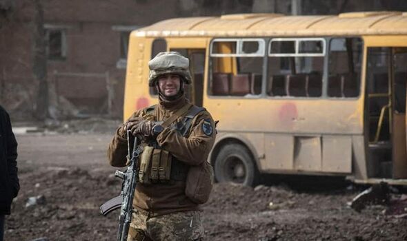 Un soldat ukrainien sourit avec du matériel détruit