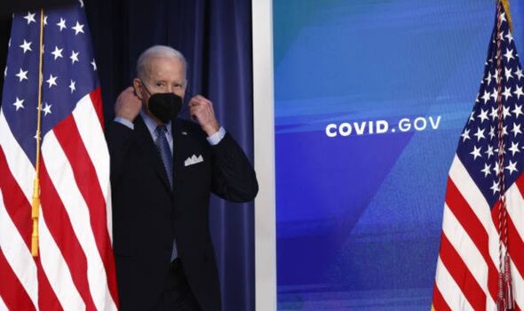 Joe Biden émergeant sur scène en portant un masque