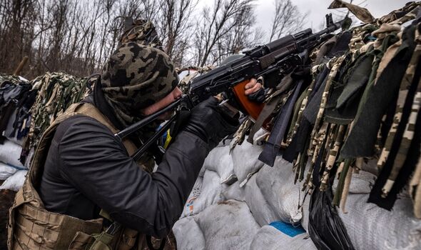 Un militaire ukrainien vise avec un fusil d'assaut depuis une tranchée sur la ligne de front à l'est de Kharkiv