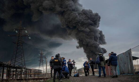Des journalistes et des habitants se tiennent debout alors que la fumée monte après une attaque de l'armée russe à Odessa