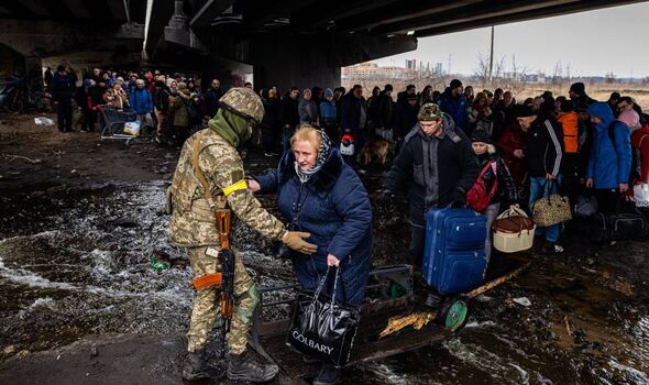Un militaire ukrainien aide les évacués rassemblés sous un pont détruit, alors qu'ils fuient la ville d'Irpin