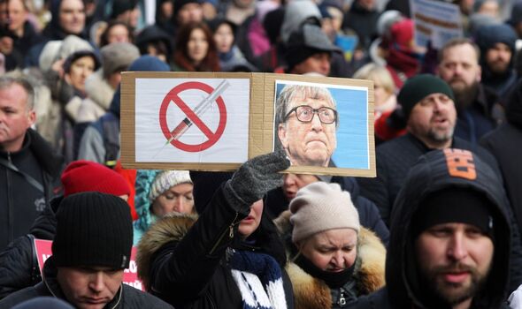 Femme portant une pancarte avec un portrait de Bill Gates lors d'une manifestation anti-vaccination.