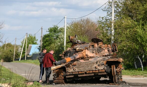 Des hommes explorent un char brûlé dans la rue dans le village de Zahaltsi près de Kiev.