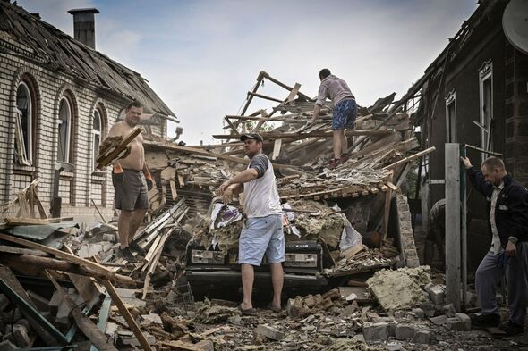 Les gens nettoient les débris de leur maison détruite après une frappe de missile, qui a tué une vieille femme