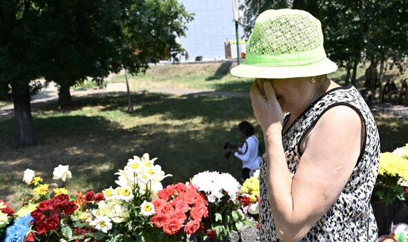 Une femme réagit devant des fleurs et des jouets pour enfants à côté d'un centre commercial détruit à Krementchouk