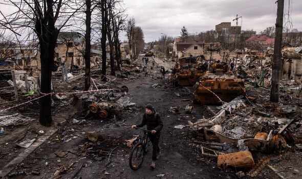 Un homme pousse son vélo à travers des débris et détruit des véhicules militaires russes dans une rue le 06 avril 2022 à Bucha