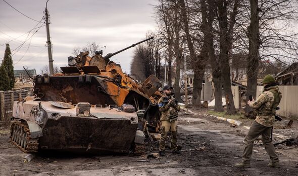 Des membres de l'armée ukrainienne prennent une photo devant des véhicules militaires russes détruits