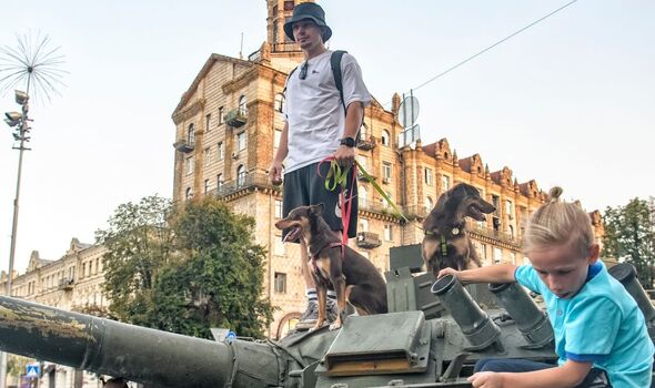 Un homme et ses chiens se tiennent sur un char alors que des enfants grimpent sur le char.