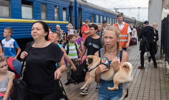 Une fille portant son chien dans ses bras essayant de monter dans le train d'évacuation à la gare de Pokrovsk dans la région de Donetsk