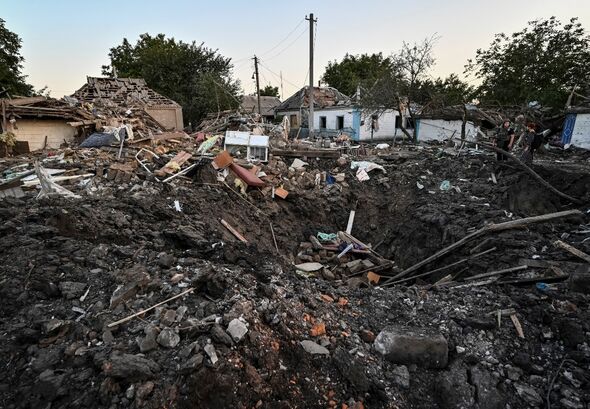 Des gens se tiennent à côté d'une maison d'habitation détruite par une frappe militaire russe