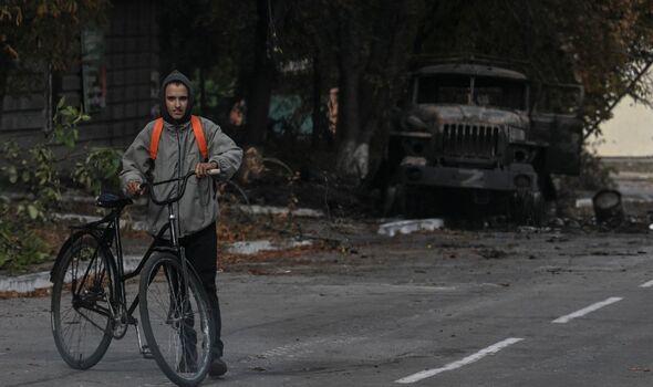 Un homme à vélo passe devant un véhicule militaire détruit à Balakliya