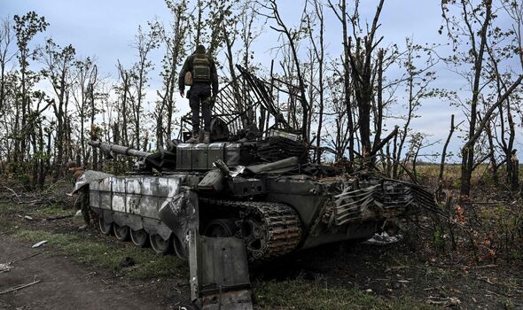 Soldat ukrainien se tenant au sommet d'un char russe abandonné près d'un village à la périphérie d'Izyum, Kharkiv.