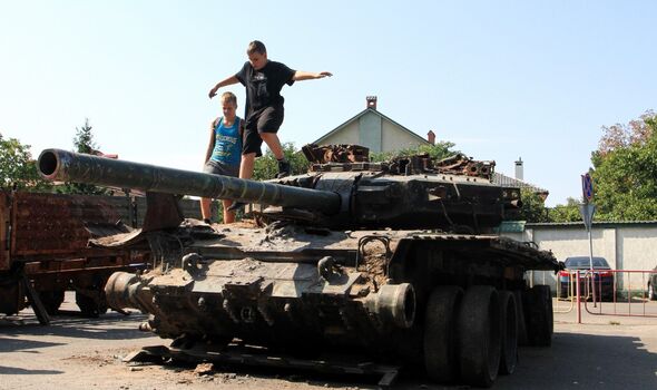Des adolescents sont vus sur la tourelle d'un char russe T-90 brûlé