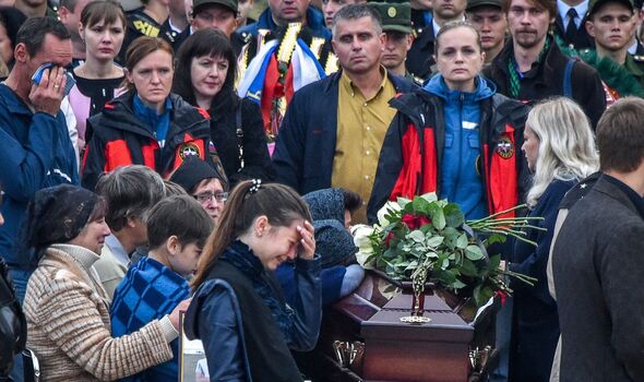 Des personnes lors d'une cérémonie funéraire en Crimée après qu'un étudiant a ouvert le feu dans un collège technique