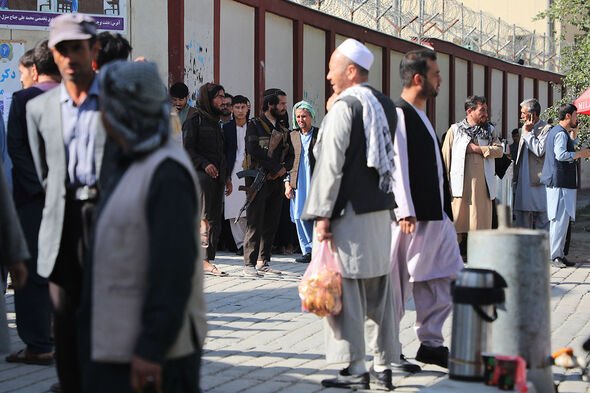 Des combattants talibans (C) montent la garde alors que des personnes se rassemblent pour rechercher des proches à l'extérieur d'un hôpital de Kaboul, le 30 septembre 2022.
