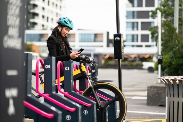 Femme en station urbaine avec vélo électrique et déplacements en ville.