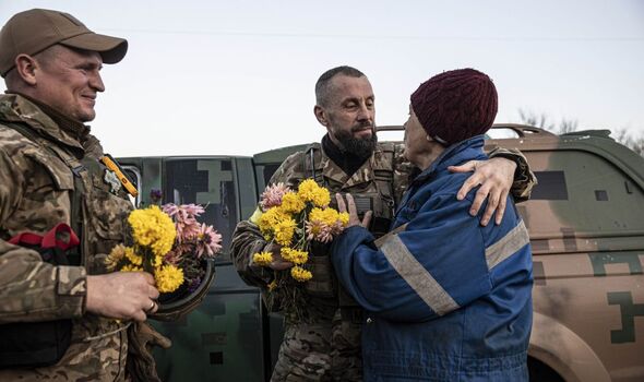 Photo d'une femme âgée offrant des fleurs aux soldats 