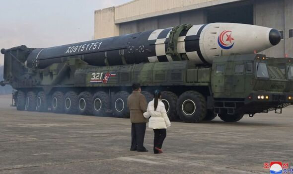 Photo du père et de la fille se tenant à côté d'un gros missile.