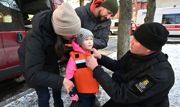 Des volontaires essaient un gilet pare-balles pour enfants sur Zlata, une Ukrainienne de six ans à Kharkiv