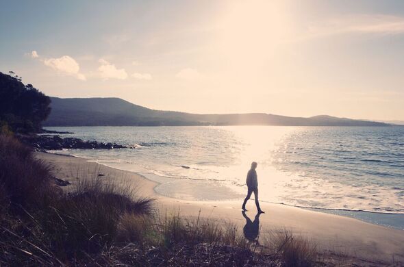 Femme se promenant sur la plage au coucher du soleil
