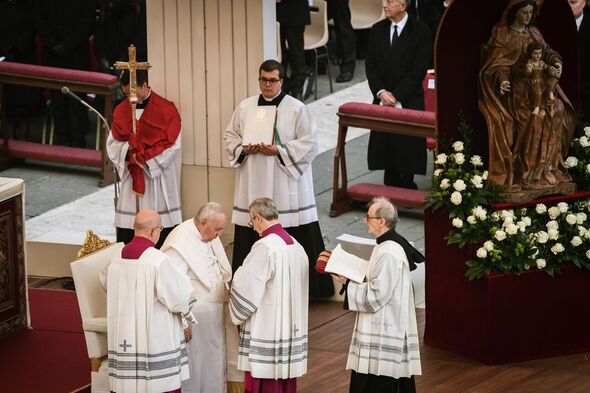 Des cardinaux aident le Pape François (C) pendant le...