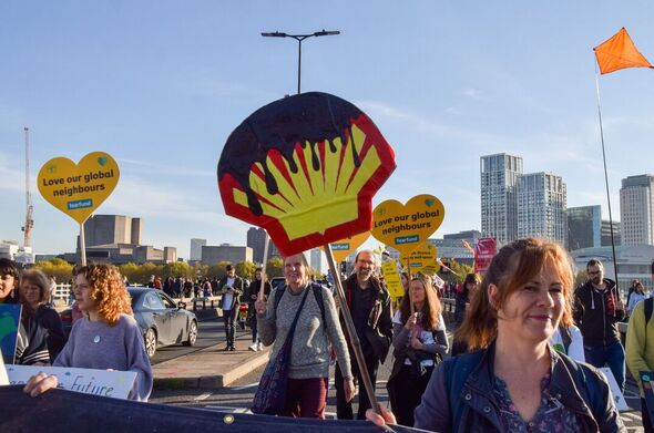 Un manifestant tient une pancarte en forme de logo Shell...