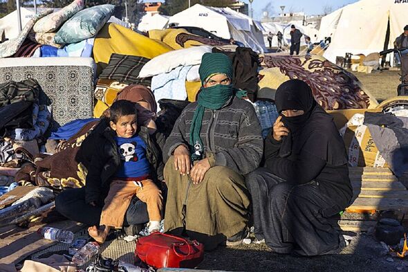 Une famille assise au milieu des couvertures dans le camp