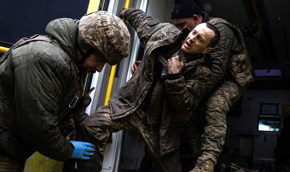 Des médecins militaires ukrainiens aident leur camarade blessé à sortir d'une ambulance près de Bakhmut 