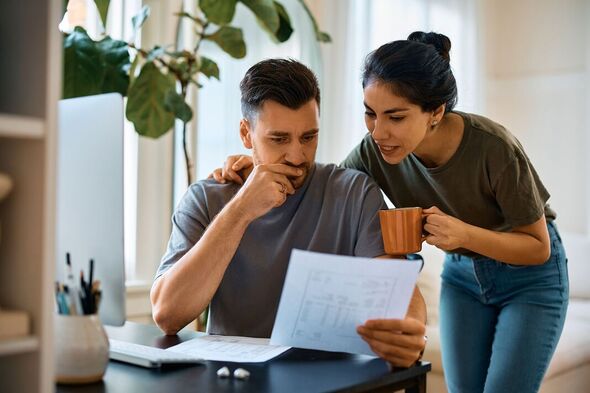 Couple d'adultes de taille moyenne analysant leurs finances à la maison.