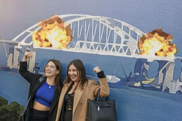 Les gens posent pour des photos devant la grande affiche représentant le pont de Crimée Kertch en feu