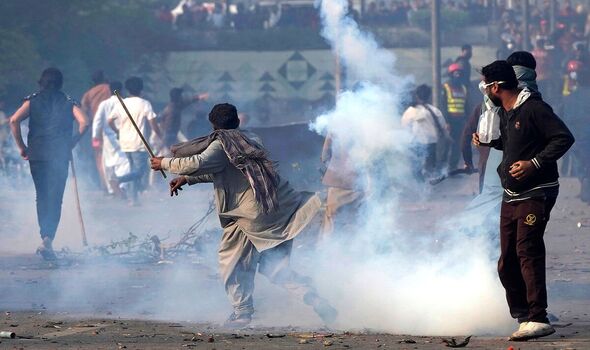 Un partisan de Khan rejette un obus de gaz lacrymogène tiré par des policiers anti-émeutes.