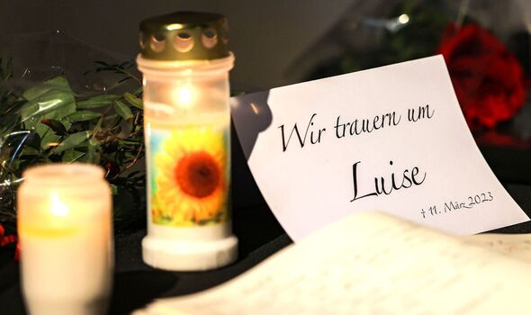 Un livre de condoléances est affiché à côté de fleurs et de bougies dans une église