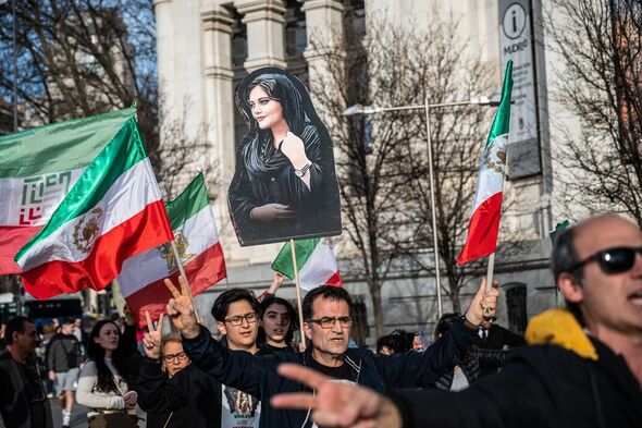 Des gens agitant des drapeaux iraniens et portant une photo de Masha...