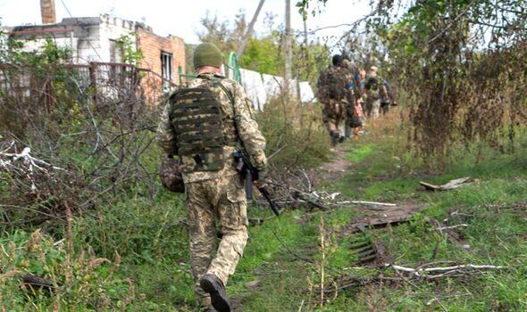 Des militaires ukrainiens passent devant des maisons d'habitation détruites à Dementiivka