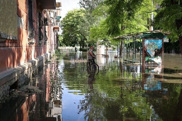 Un résident local se tient avec son vélo dans une rue inondée de la ville de Kherson'