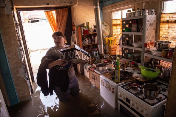 Une femme récupère des affaires chez elle dans une zone inondée...